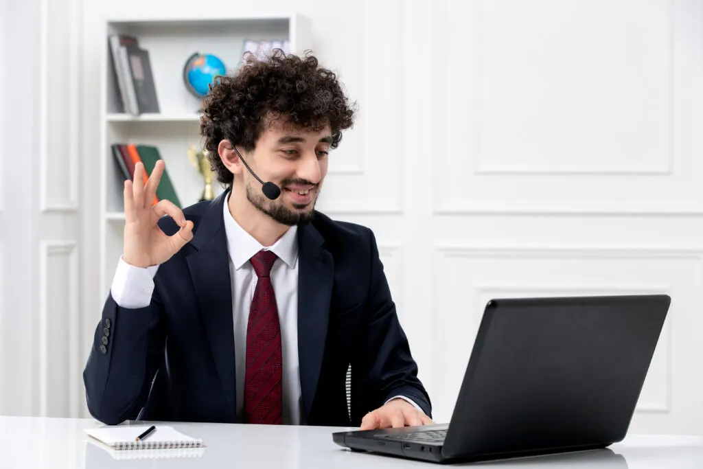 customer service handsome young guy office suit with laptop headset showing ok gesture scaled